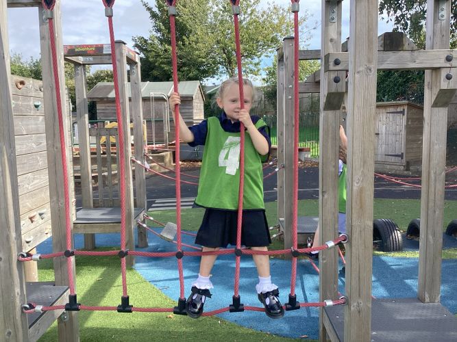 Child playing in the school playground on a rope bridge