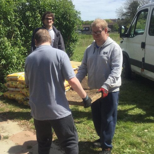 Two gardeners laying paving slabs.